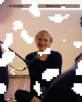 a femme presenting person with the short blond hair smiling. while looking just beyond the camera.